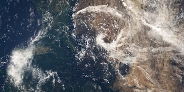 A satellite image showing the formation of a hurricane over warm ocean waters. The image highlights the swirling cloud patterns and the eye of the storm.