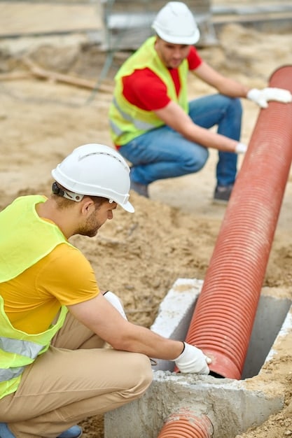A group of construction workers installing a new water pipeline underground in a residential area, emphasizing infrastructure improvement.