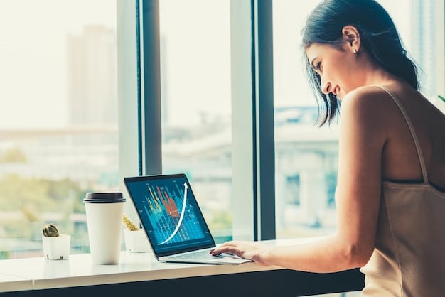A person using a laptop and looking at graphs and charts displayed on the screen, smiling, in front of a big window with city view.